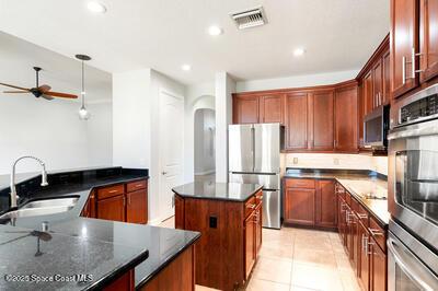 kitchen featuring arched walkways, visible vents, appliances with stainless steel finishes, a sink, and dark stone counters