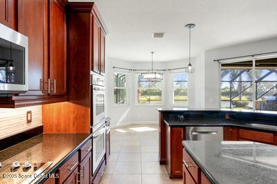 kitchen with light tile patterned floors, stainless steel appliances, visible vents, dark stone countertops, and dark brown cabinets