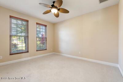 empty room with a ceiling fan, light colored carpet, visible vents, and baseboards