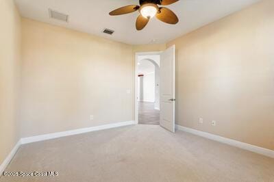 carpeted empty room with a ceiling fan, visible vents, and baseboards