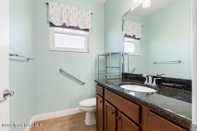 bathroom featuring toilet, baseboards, and vanity