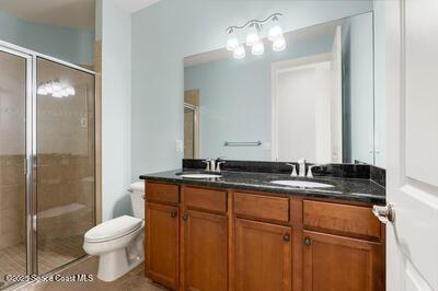 bathroom featuring a sink, a shower stall, and double vanity