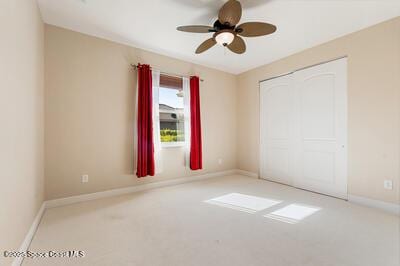 empty room with light carpet, baseboards, and a ceiling fan