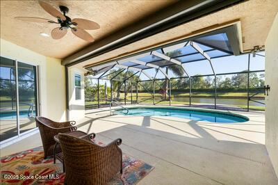 pool with a lanai, a patio area, and ceiling fan