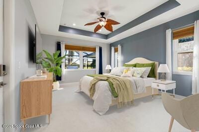 bedroom with a raised ceiling and light colored carpet