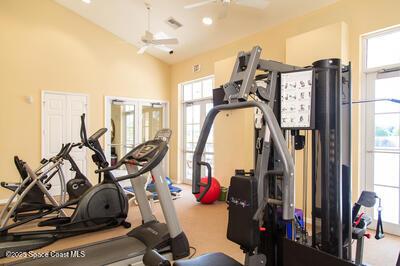 exercise area featuring carpet floors, visible vents, ceiling fan, and high vaulted ceiling