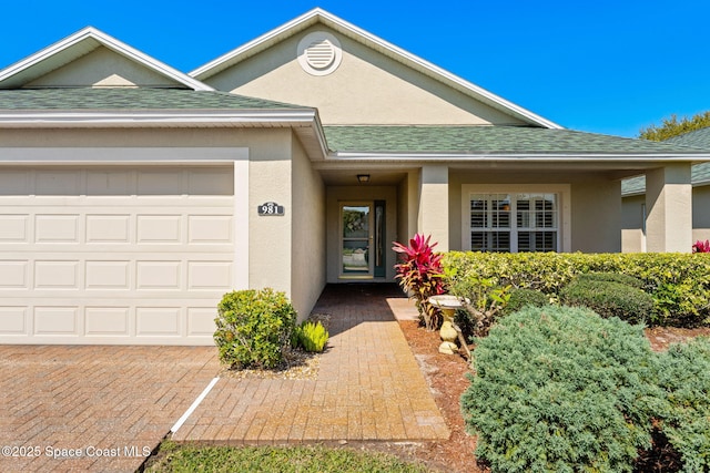 view of front of house featuring a shingled roof, an attached garage, and stucco siding