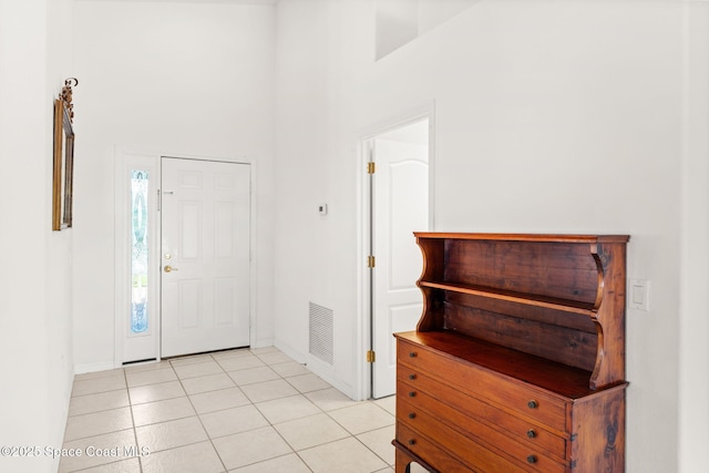 foyer entrance with visible vents, a towering ceiling, baseboards, and light tile patterned floors