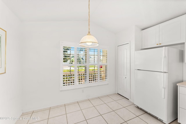 unfurnished dining area featuring light tile patterned floors and vaulted ceiling