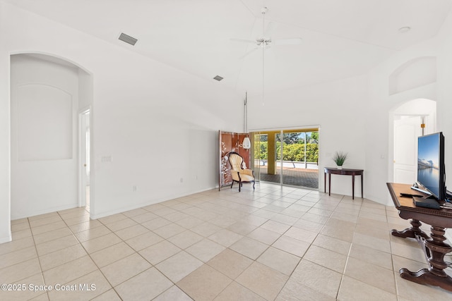 living area featuring light tile patterned floors, visible vents, arched walkways, and high vaulted ceiling