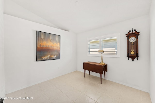 empty room featuring vaulted ceiling and baseboards