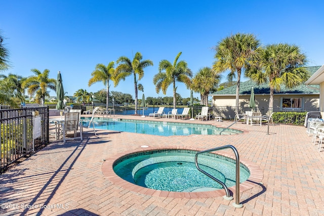 community pool featuring a patio area, a hot tub, and fence