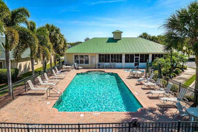 pool featuring a sunroom, a patio area, and fence