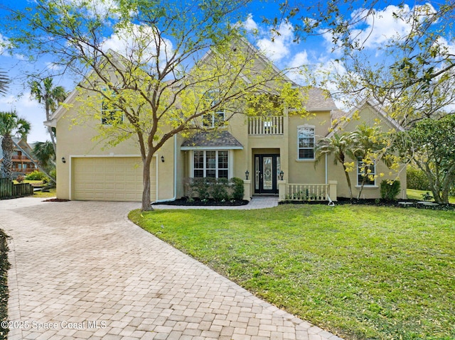 view of front of property with a garage, a front yard, decorative driveway, and stucco siding