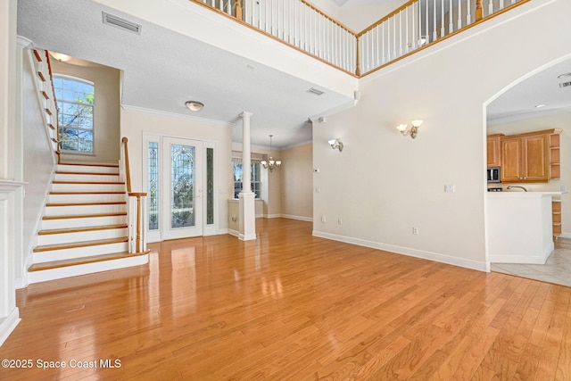 foyer with stairs, light wood-style flooring, visible vents, and crown molding