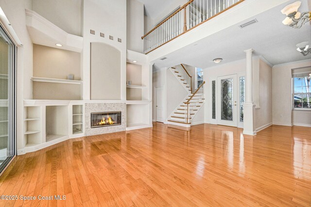 unfurnished living room with baseboards, visible vents, hardwood / wood-style flooring, ornamental molding, and stairs