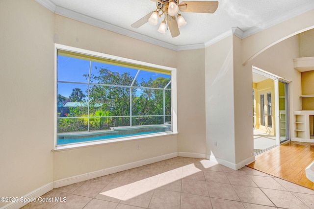 tiled empty room featuring crown molding, baseboards, and ceiling fan