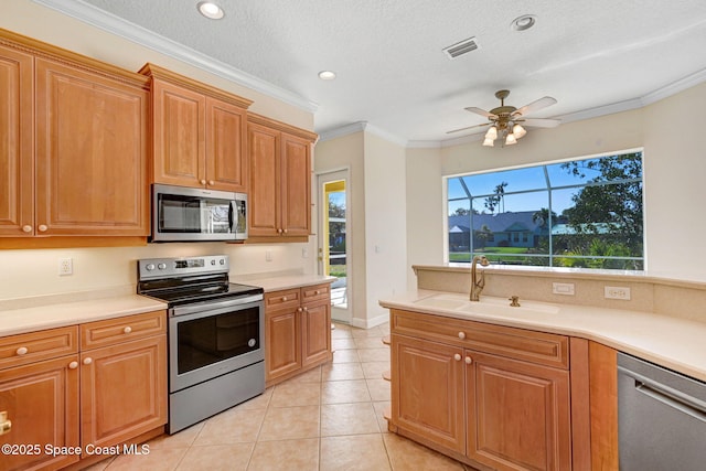 kitchen with visible vents, appliances with stainless steel finishes, ornamental molding, light countertops, and a sink