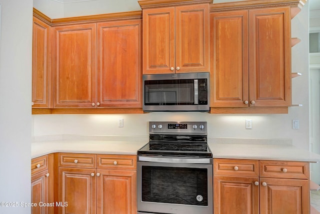 kitchen with light countertops, appliances with stainless steel finishes, and brown cabinetry