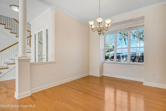 unfurnished dining area featuring wood-type flooring, stairway, a chandelier, and crown molding