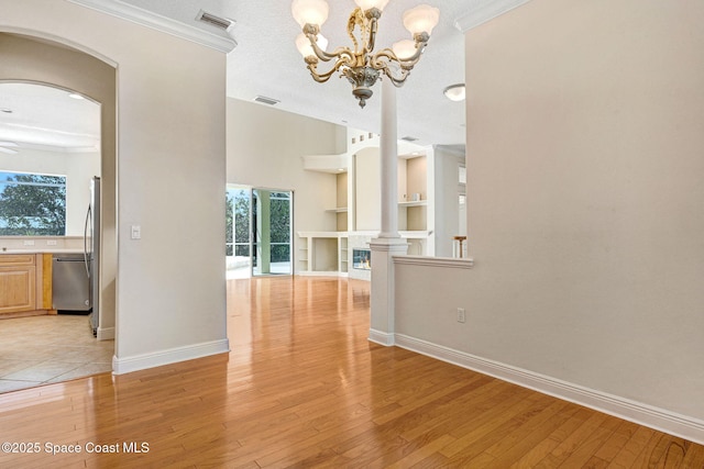 unfurnished dining area featuring baseboards, light wood-type flooring, visible vents, and built in features