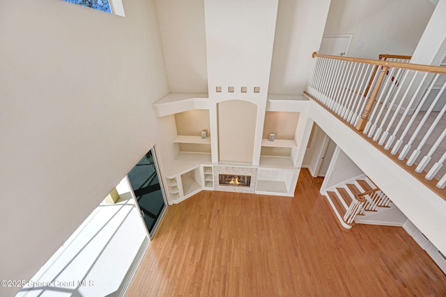 unfurnished living room featuring built in shelves, wood finished floors, and a tile fireplace