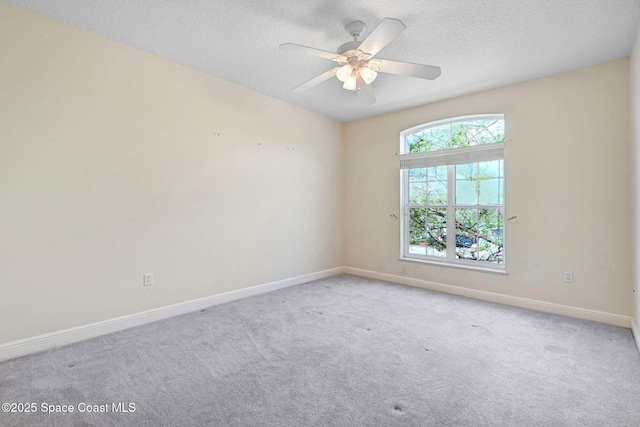 carpeted empty room with a ceiling fan, a textured ceiling, and baseboards