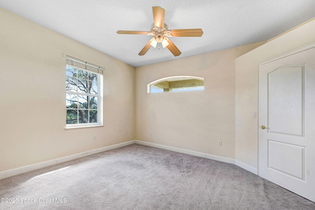 carpeted spare room featuring a ceiling fan, a textured ceiling, and baseboards