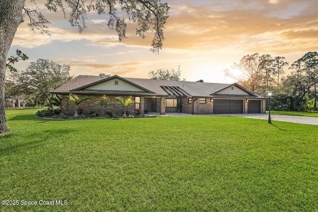 view of front facade featuring a garage, concrete driveway, a front lawn, and brick siding