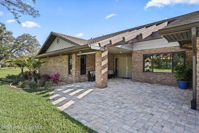 exterior space with a patio area, a yard, and brick siding