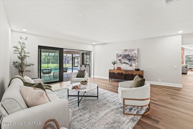 living room featuring a textured ceiling, recessed lighting, wood finished floors, and baseboards