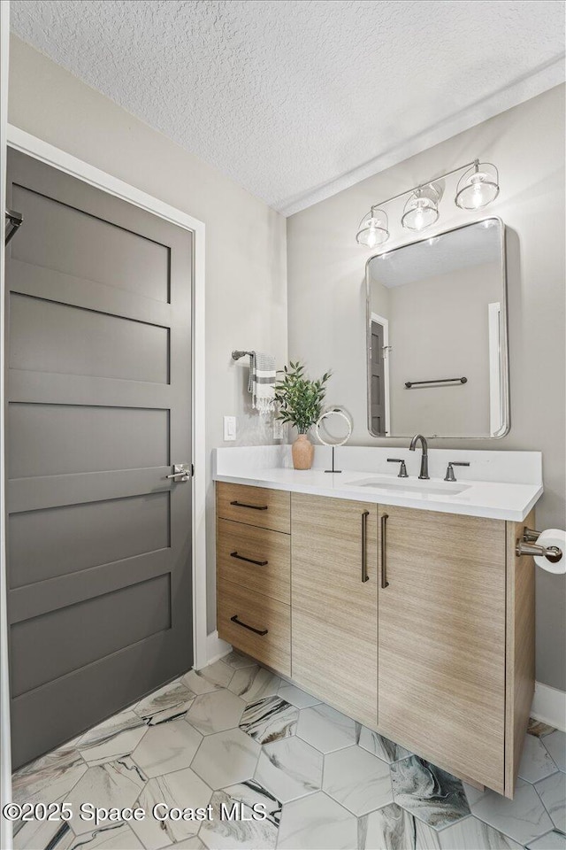 bathroom with marble finish floor, a textured ceiling, and vanity