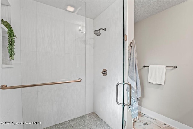 full bathroom with marble finish floor, a shower stall, baseboards, and a textured ceiling