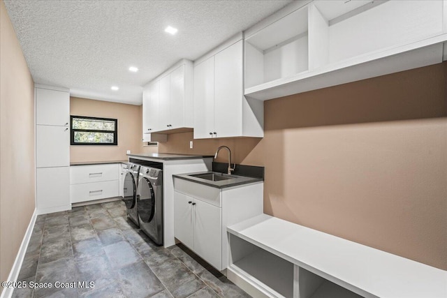 laundry room featuring cabinet space, a sink, a textured ceiling, independent washer and dryer, and baseboards