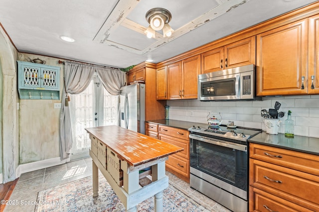 2109 Indian River Dr, Cocoa, FL 32922 - kitchen with stainless steel appliances, dark countertops, brown cabinets, and tasteful backsplash