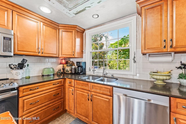 2109 Indian River Dr, Cocoa, FL 32922 - kitchen featuring appliances with stainless steel finishes, a sink, dark countertops, brown cabinets, and backsplash