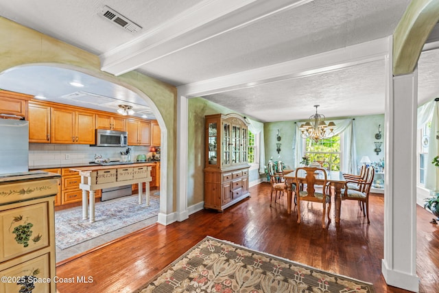 2109 Indian River Dr, Cocoa, FL 32922 - dining room featuring dark wood finished floors, baseboards, a chandelier, a textured ceiling, and arched walkways