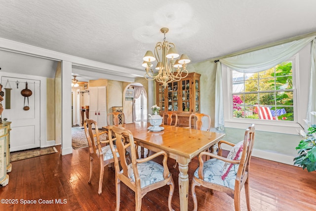 2109 Indian River Dr, Cocoa, FL 32922 - dining space with dark wood finished floors, a chandelier, arched walkways, a textured ceiling, and baseboards