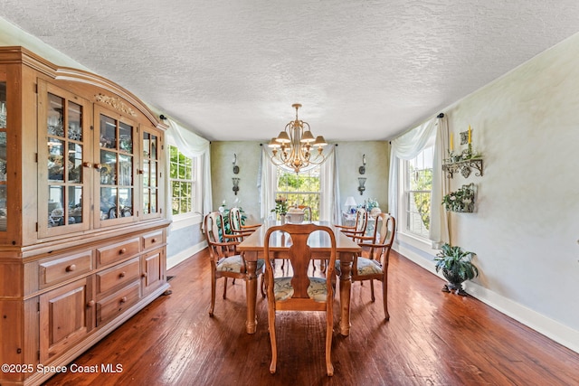2109 Indian River Dr, Cocoa, FL 32922 - dining space featuring a chandelier, baseboards, a textured ceiling, plenty of natural light, and dark wood-type flooring