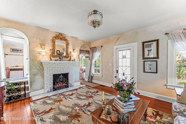 2109 Indian River Dr, Cocoa, FL 32922 - living area featuring a brick fireplace, hardwood / wood-style flooring, plenty of natural light, and baseboards