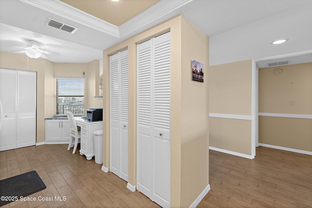 hall with light wood-style floors, baseboards, and visible vents