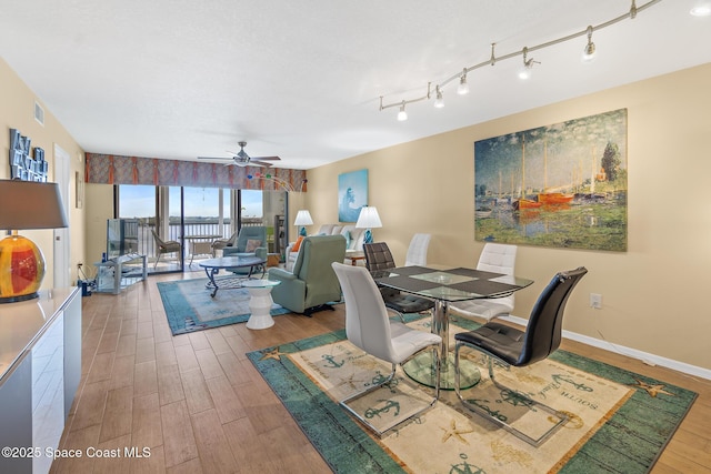 dining area with a textured ceiling, wood finished floors, a ceiling fan, baseboards, and track lighting