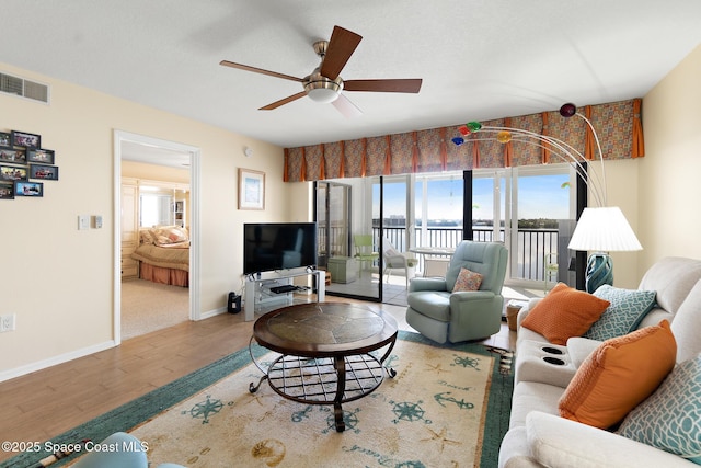 living area with plenty of natural light, wood finished floors, visible vents, and a ceiling fan