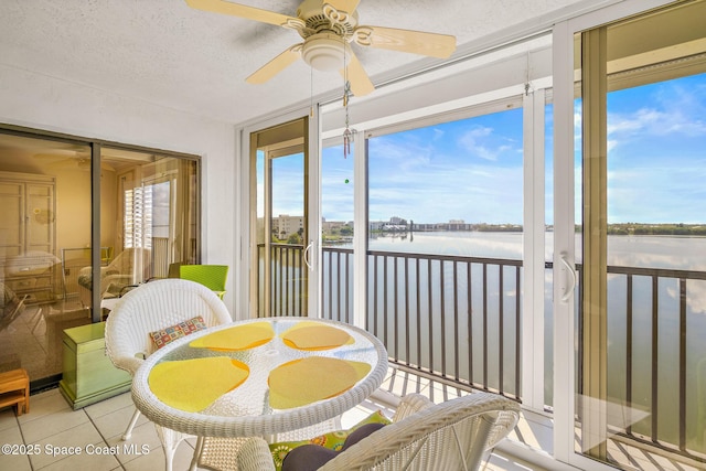 sunroom / solarium featuring a water view and a ceiling fan