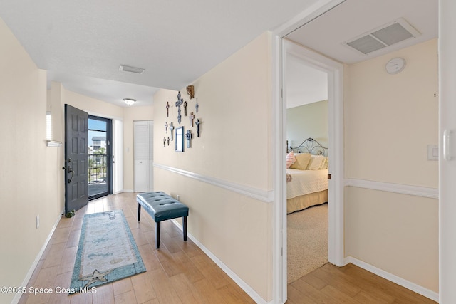 hall with baseboards, visible vents, and wood finished floors