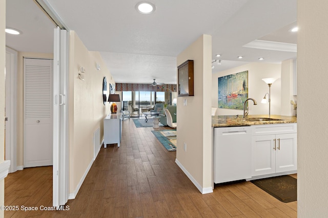 corridor with recessed lighting, a sink, baseboards, and wood finished floors