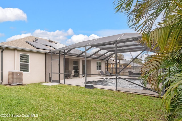 back of property featuring roof with shingles, a yard, stucco siding, roof mounted solar panels, and a patio area