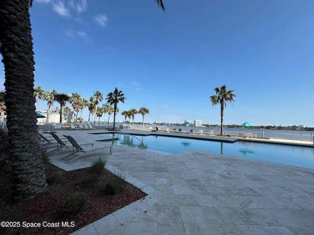 community pool with a patio area and a water view