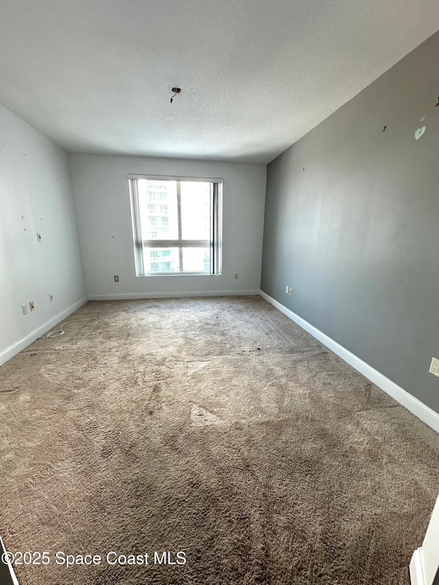 carpeted spare room with baseboards and a textured ceiling