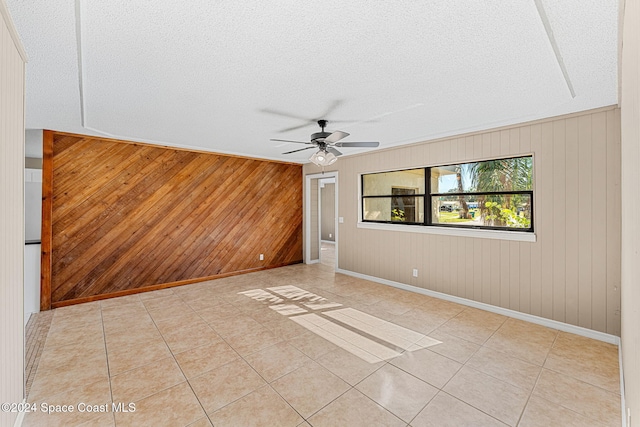 spare room featuring light tile patterned floors, ceiling fan, baseboards, and a textured ceiling